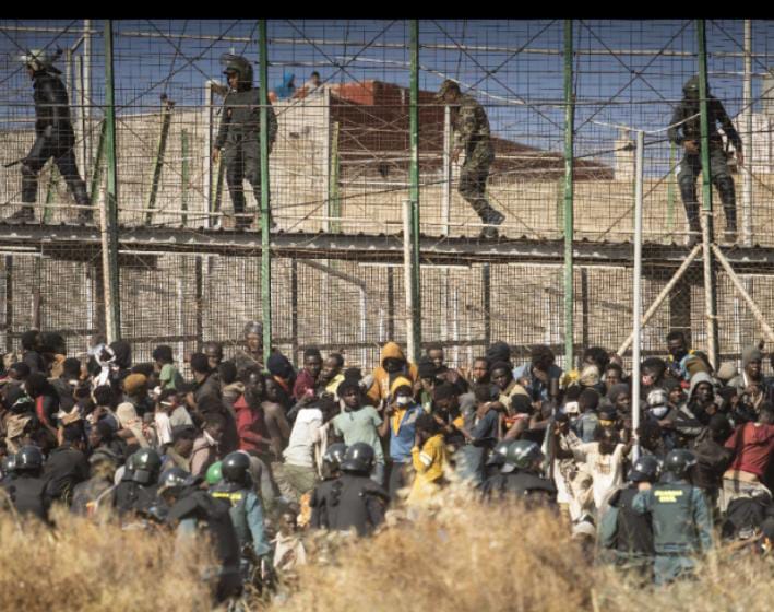 Migrantes intentando saltar la valla de Melilla, frontera sur de España