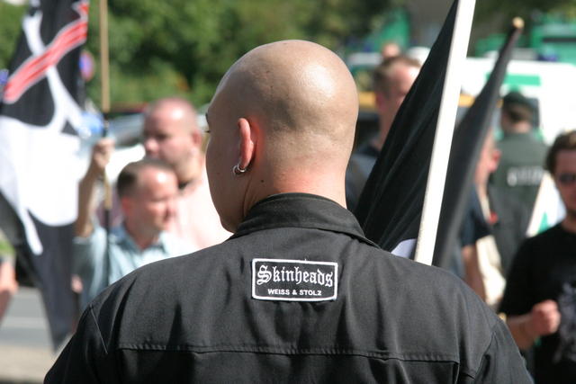 Fuente: Wikimedia Commons, CC BY-SA 3.0. Neonazi skinhead con chaqueta “Weiss & Stolz” en una manifestación.