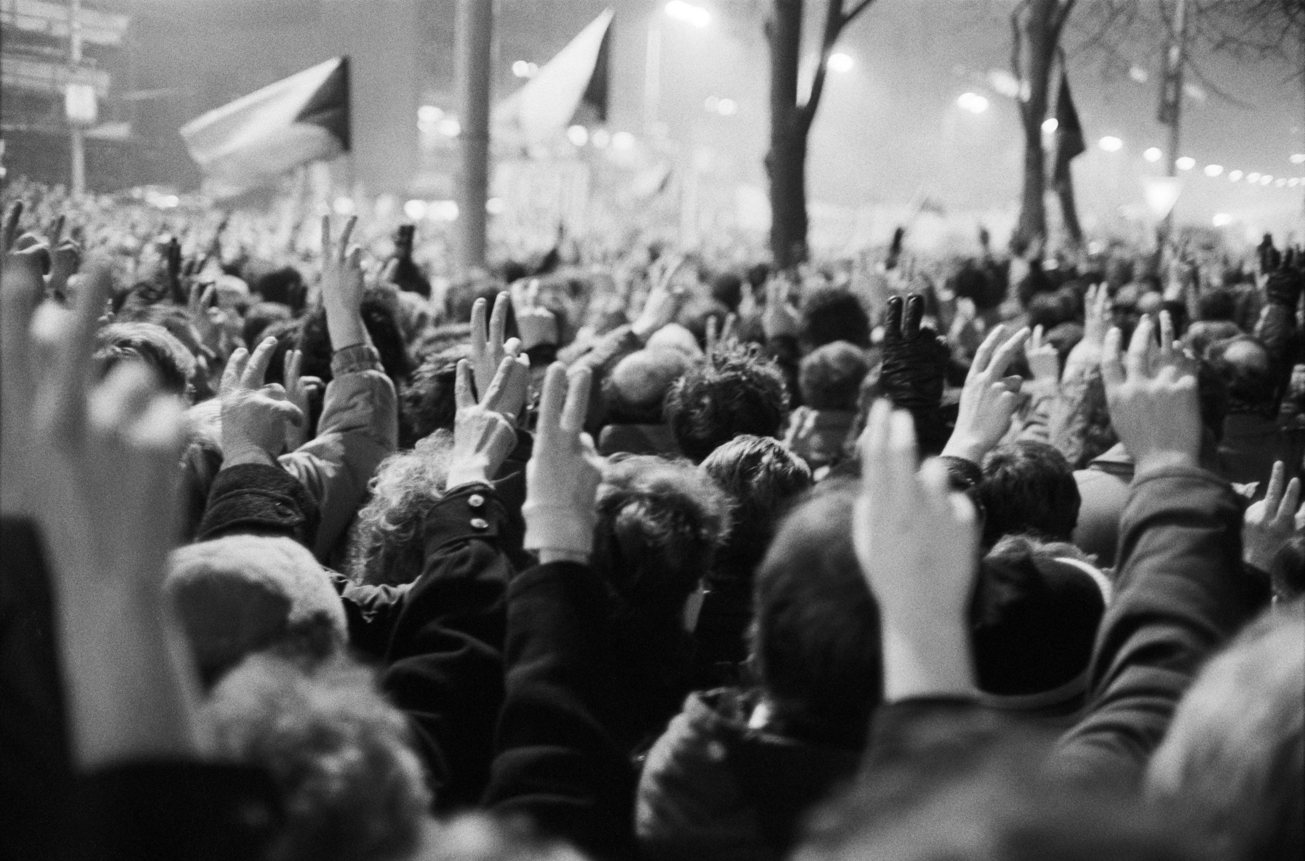 Protesta en Praga durante la Revolución de Terciopelo, 1989, con manifestantes levantando dos dedos y haciendo sonar llaves como símbolo de libertad