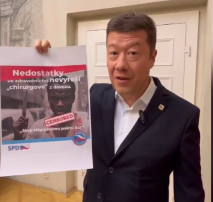 Tomio Okamura mostrando uno de sus carteles de campaña del SPD con mensajes xenófobos y racistas.